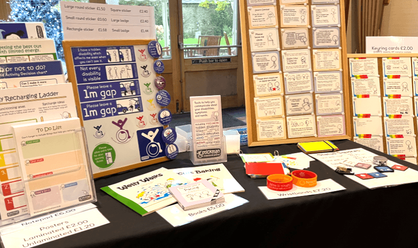 A display of communication tools for disabled people, including "Please leave a 1m gap" signs, "To Do List" notepads, and keyring cards, highlighting exclusive disabled member deals.
