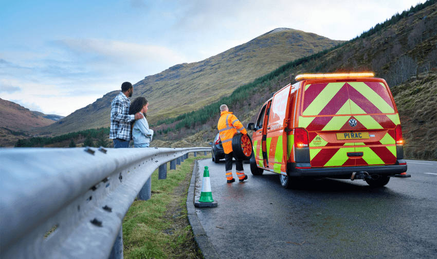 RAC breakdown mechanic assists stranded couple on scenic mountain road, highlighting inclusive roadside support and emergency services.