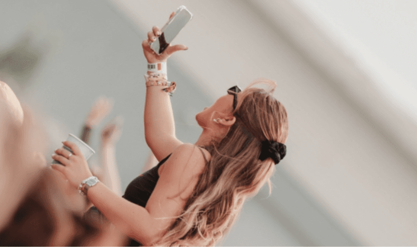 Woman taking a photo at a festival, Three Purpl discounts for disabilities and long term health conditions, disabled travel discounts UK.