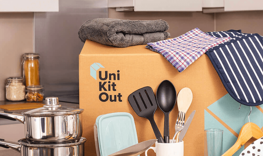 Uni Kit Out box in a kitchen surrounded by household essentials including stainless steel saucepans, utensils, folded towels, and tea towels, representing a kitchen essentials bundle, homeware starter kit discounts, and mobility-friendly home starter packs.