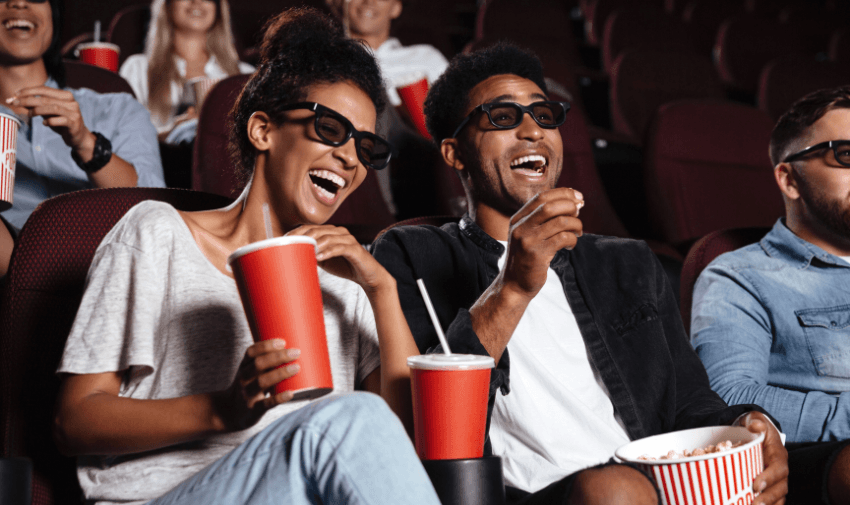 A cheerful group enjoying a 3D film at the cinema, wearing glasses and holding popcorn and drinks. Ideal for showcasing disabled cinema ticket discounts UK and accessible entertainment deals.