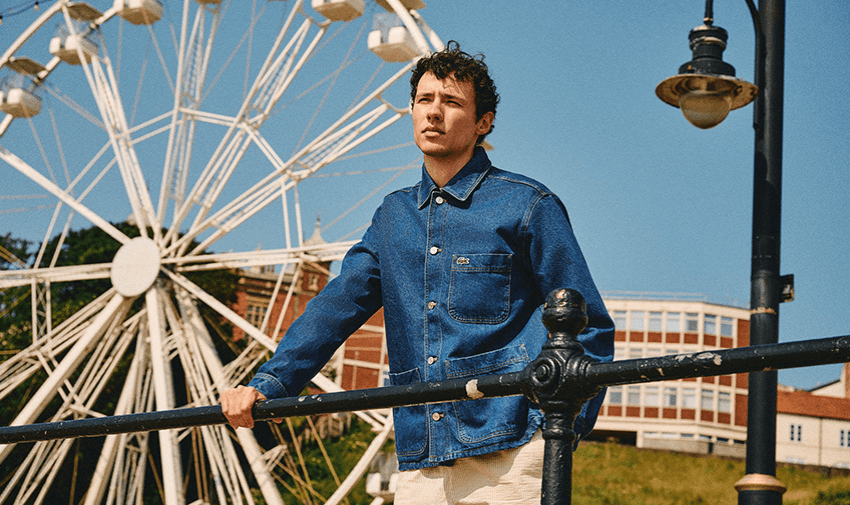 A man in a denim jacket standing in front of a Ferris wheel, showcasing shopping discounts for disabled people.