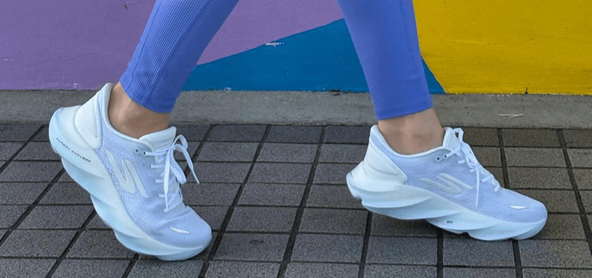 Person walking in white and lilac Skechers trainers paired with purple leggings against a colourful background – lightweight supportive trainers with disabled footwear discounts for active lifestyles and walking comfort.