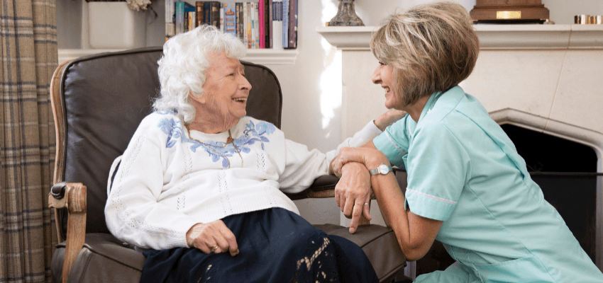 Friendly nurse chatting with elderly woman in armchair, Trinity Homecare Accessibility Discounts UK and Carer Savings.