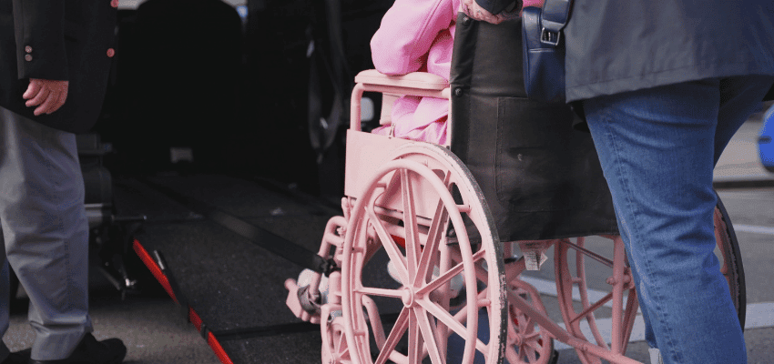 Person in a wheelchair being assisted up a WAV ramp. Accessible travel savings, mobility support offers, discounts for disabled people in the UK.
