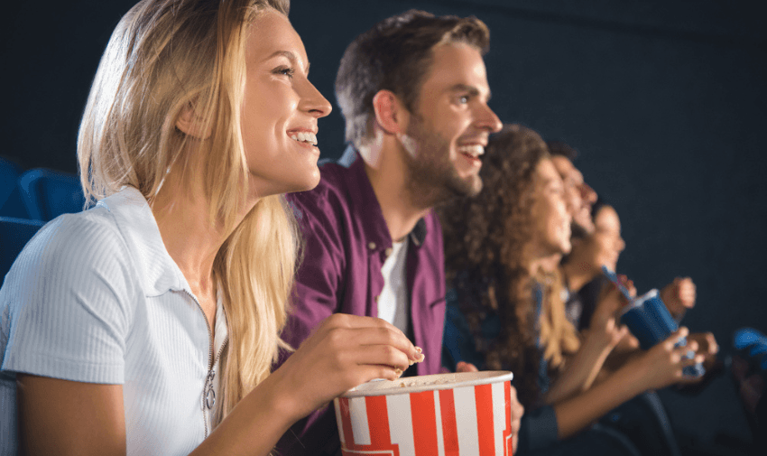 Smiling cinema-goers eating popcorn and enjoying a movie screening, showcasing inclusive film experiences and affordable cinema discounts for disabled adults in the UK.