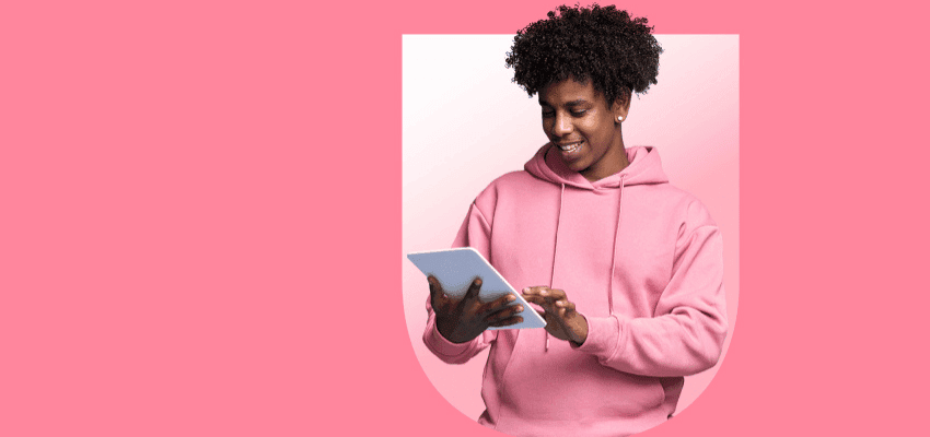 Smiling woman in pink hoodie using tablet on pink background promoting affordable broadband deals with disabled discounts in the UK