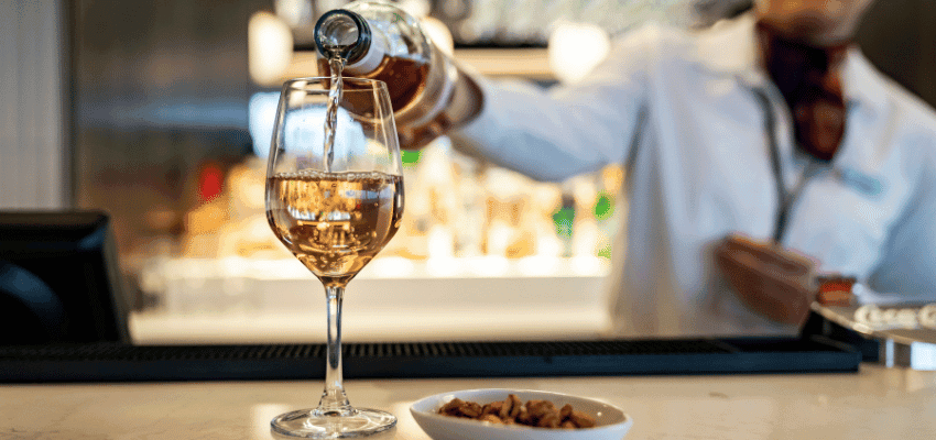 Bartender pouring white wine at bar, Holiday Extras Purpl discounts for disabilities and long term health conditions, disabled travel discounts UK.