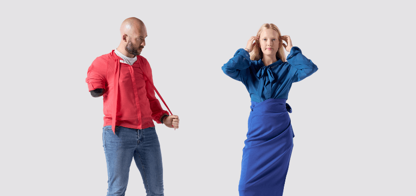 A man with a limb difference wearing a red adaptive jacket and jeans stands confidently beside a woman in an elegant blue adaptive outfit designed to comfortably cover and support a stoma bag, promoting inclusive fashion choices for disabled people, Shopping Discounts for Disabled People, disability clothing UK, and adaptive fashion support.