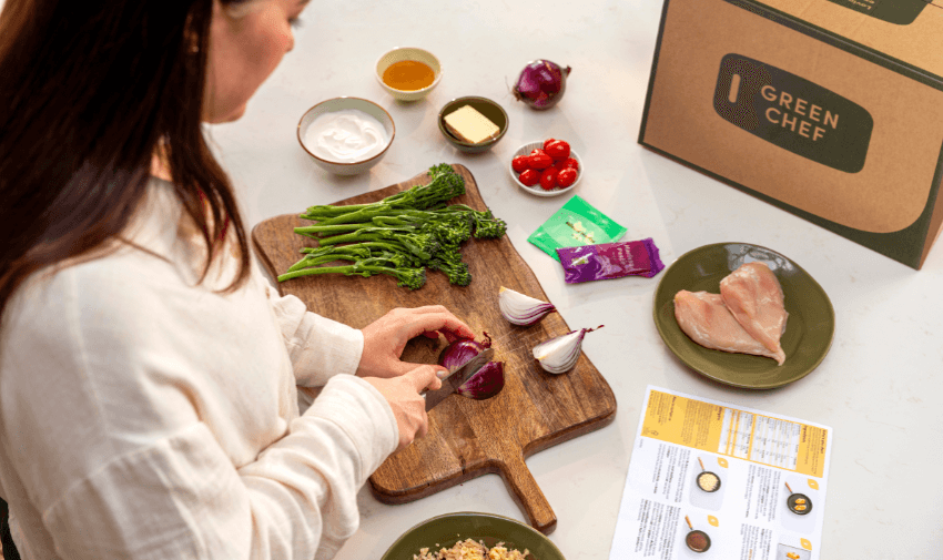 A woman chopping a red onion with fresh ingredients and a Green Chef meal box on the counter, highlighting shopping discounts for disabled people.
