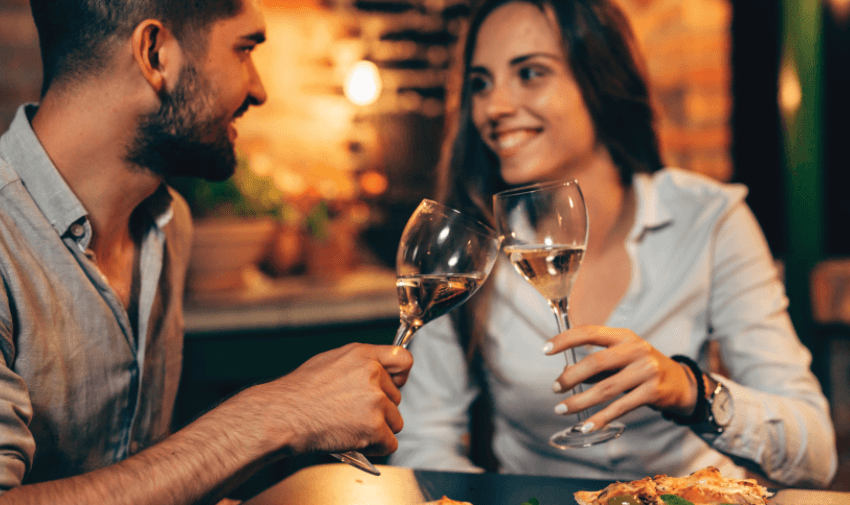 Couple enjoying dinner and clinking wine glasses at a restaurant promoting experience gifts with disabled discounts in the UK