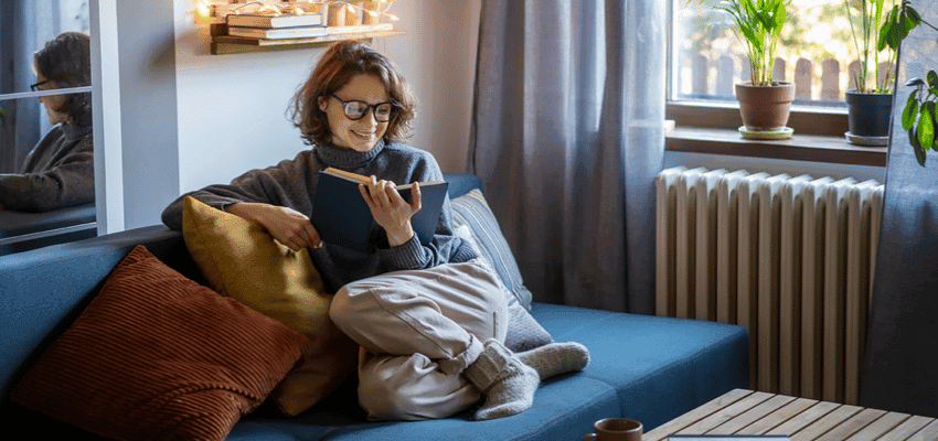 Woman reading on sofa in cosy living room, Books2Door Purpl discounts for disabilities and long term health conditions, shopping discounts for disabled people.