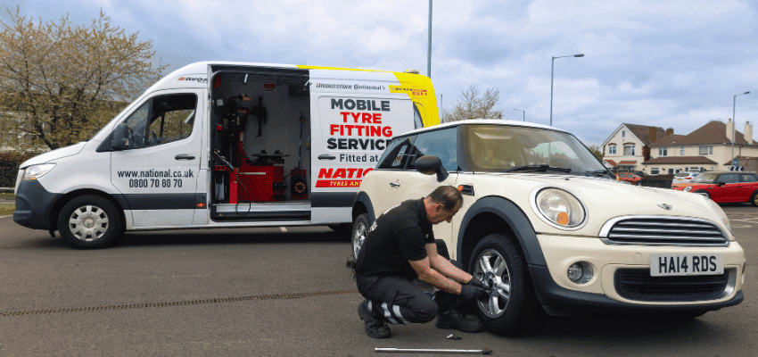National Tyres mobile fitting van with mechanic changing car tyre Purpl disabled discounts members save on tyre replacements and roadside services