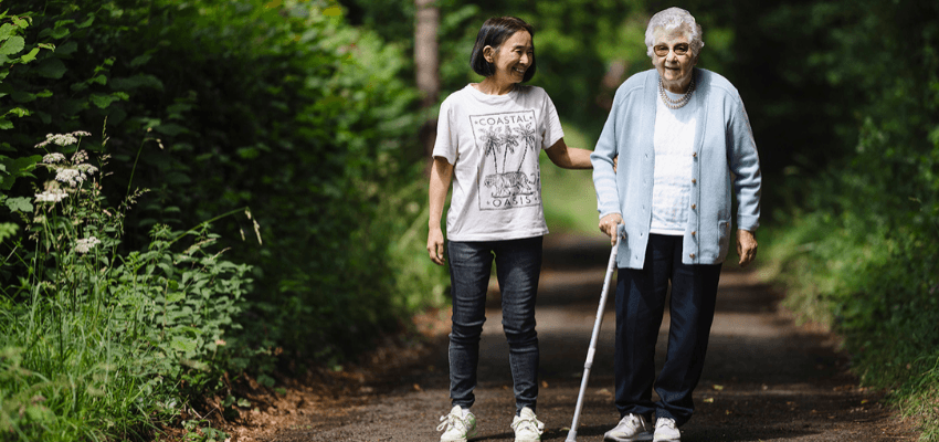 Carer supporting older woman walking outdoors, Trinity Homecare Purpl discounts for disabilities and long term health conditions, mobility discounts and offers.