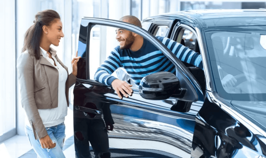 Smiling couple exploring a new car at a dealership – accessible car finance advice with inclusive gap insurance discounts for disabled drivers UK.