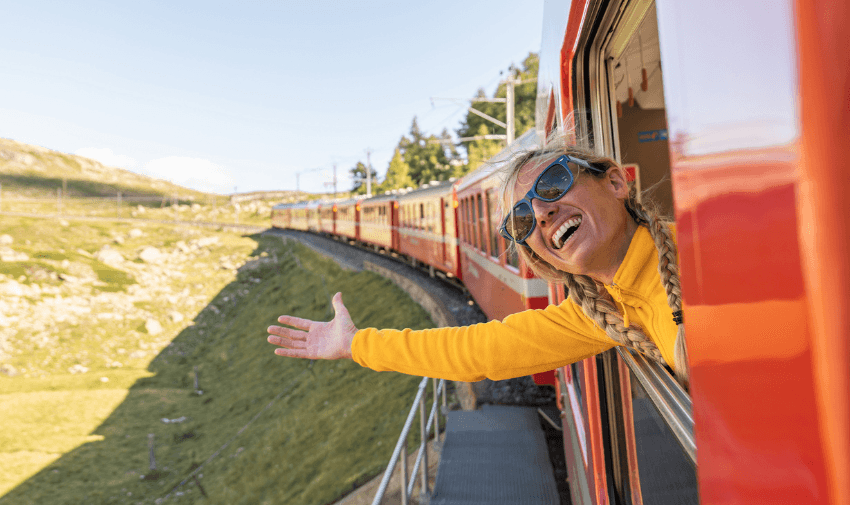 Woman leaning from red train window, TrainPal Purpl discounts for disabilities and long term health conditions, disabled travel discounts UK.