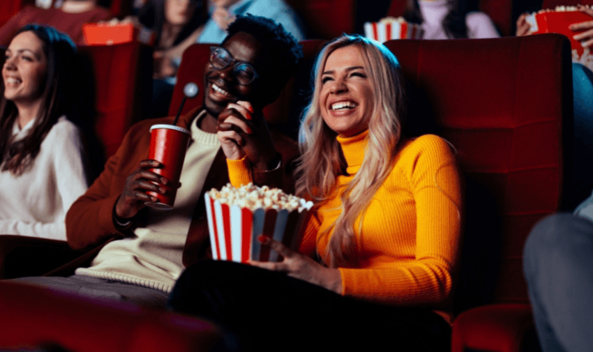 Couple laughing in cinema seats with popcorn, Showcase Purpl discounts for disabilities and long term health conditions, disabled travel discounts UK.